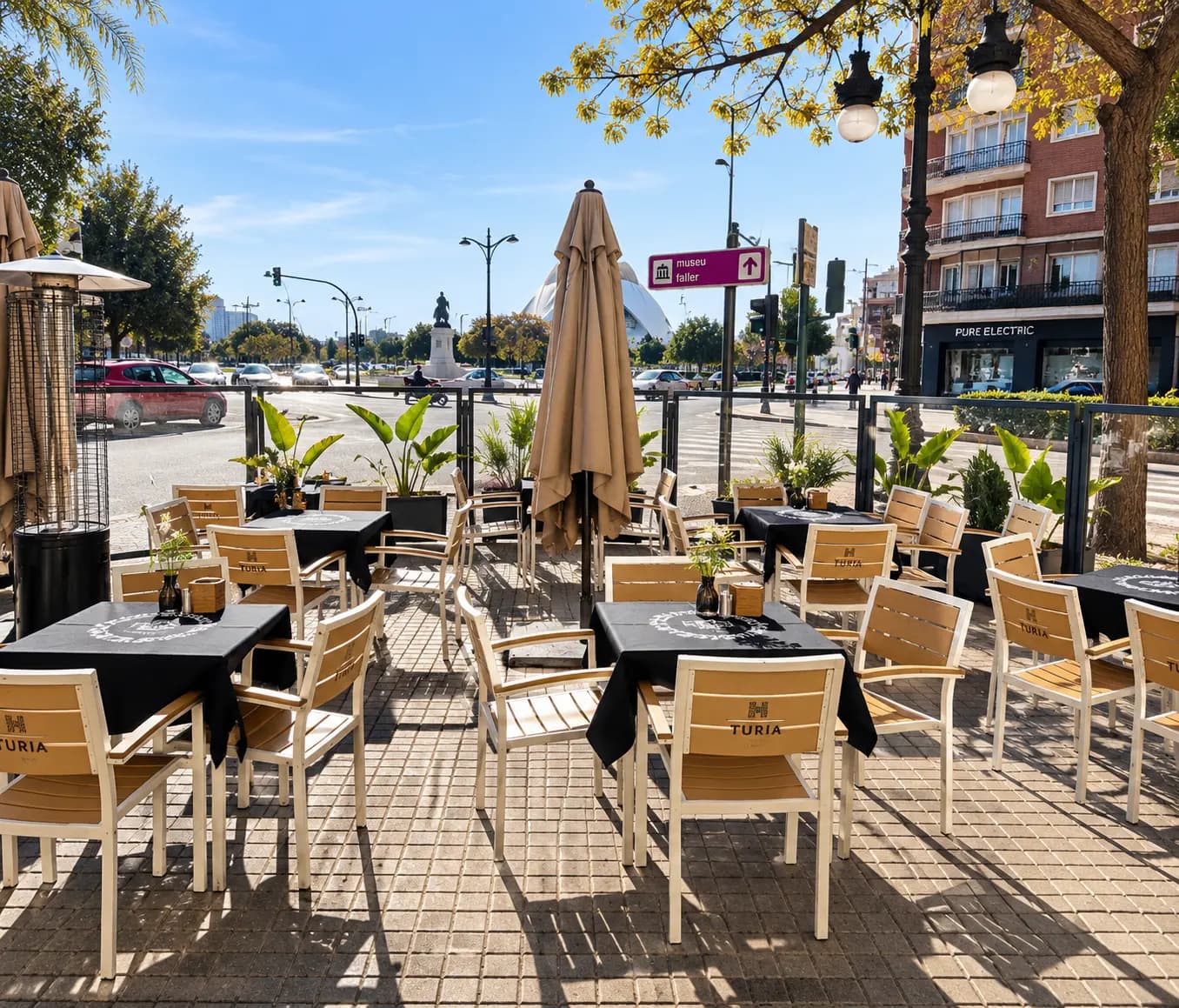 Terraza con mesas y sillas de madera y el Palau de les Arts al fondo